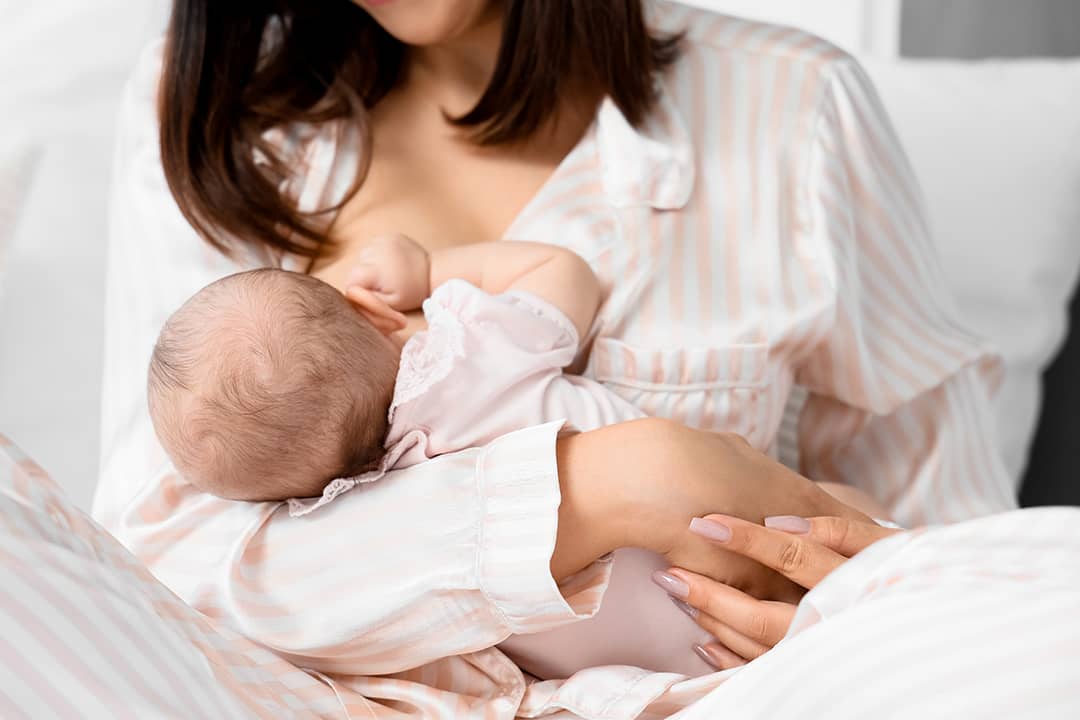A mother breastfeeding her baby in the bedroom.